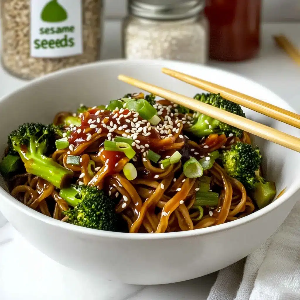 Beef and Broccoli Stir-Fry with Noodles, quick beef stir-fry recipes, easy weeknight dinner ideas, healthy Asian noodle dishes, flavorful beef and broccoli dish A white bowl holds a serving of dark brown noodles mixed with bright green broccoli pieces. On top, there are white sesame seeds scattered along with small green slices of spring onion. A red sauce is drizzled over the dish, adding a pop of color. Two light-colored wooden chopsticks rest on the bowl's edge, slightly lifting the noodles and vegetables. The bowl sits on a white marbled surface, with a glass jar labeled 