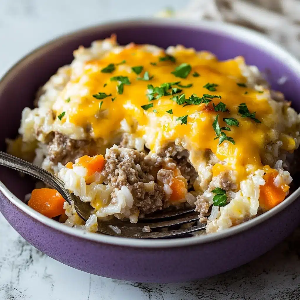 Cheesy Ground Beef and Rice Casserole, ground beef casserole recipe, cheesy rice bake, easy beef and rice dish, comfort food casserole The image shows a serving of rice casserole in a white bowl with a purple inside. The dish has at least three layers: the bottom is a mix of cooked white rice and small pieces of ground meat with bits of orange carrots; the middle layer shows melted yellow cheese that covers the rice and meat mix; small green herbs are sprinkled on top, adding fresh color. A silver fork is resting on the edge of the bowl. The background is a white marbled texture.