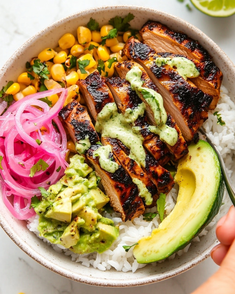 Caramelized BBQ Chicken Thighs in the Oven, BBQ chicken thigh recipes, baked BBQ chicken, oven-roasted BBQ chicken, easy chicken dinner recipes A white bowl filled with a base layer of white rice and small pieces of yellow corn scattered around. On top, there are slices of grilled dark brown chicken with a slightly charred texture, drizzled with a creamy pale green sauce. To one side, there are bright pink pickled onions in thin rings, while on the opposite side, a few slices of light green avocado rest near a lime wedge. Shredded pale green cabbage is layered next to the avocado. The dish is sprinkled with small bits of fresh green herbs. A silver fork is placed on the chicken, and a woman's hand is reaching towards the bowl from the bottom right corner. The bowl sits on a white marbled surface.