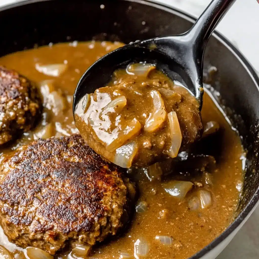 Hamburger Steak with Mushroom Gravy, hearty hamburger steak recipes, savory mushroom gravy dishes, comforting home-cooked meals, easy ground beef recipes The image shows a close-up of two browned burger patties in a white cast iron pan filled with thick brown gravy and sliced light brown onions. A black metal spoon held by a woman's hand is lifting some of the smooth gravy, showing its thick, shiny texture with small bits in it. The patties have a rough, uneven surface with a caramelized crust. The background is a white marbled texture.
