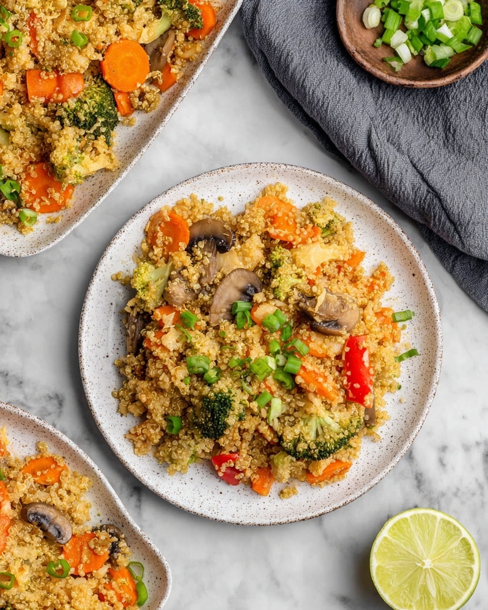 The image shows a white speckled round plate filled with warm quinoa mixed with small pieces of light brown chicken, green broccoli florets, orange carrot slices, and dark brown mushroom slices, all scattered evenly. Bright green chopped spring onions are sprinkled over the dish, adding a fresh contrast. A silver fork rests on the right side of the plate. In the background, there is a white rectangular dish filled with the same quinoa mix and part of another white speckled round plate with the same quinoa dish. The whole setting is on a white marbled surface, with a lime slice placed at the bottom right corner. Photo taken with an iphone --ar 4:5 --v 7
