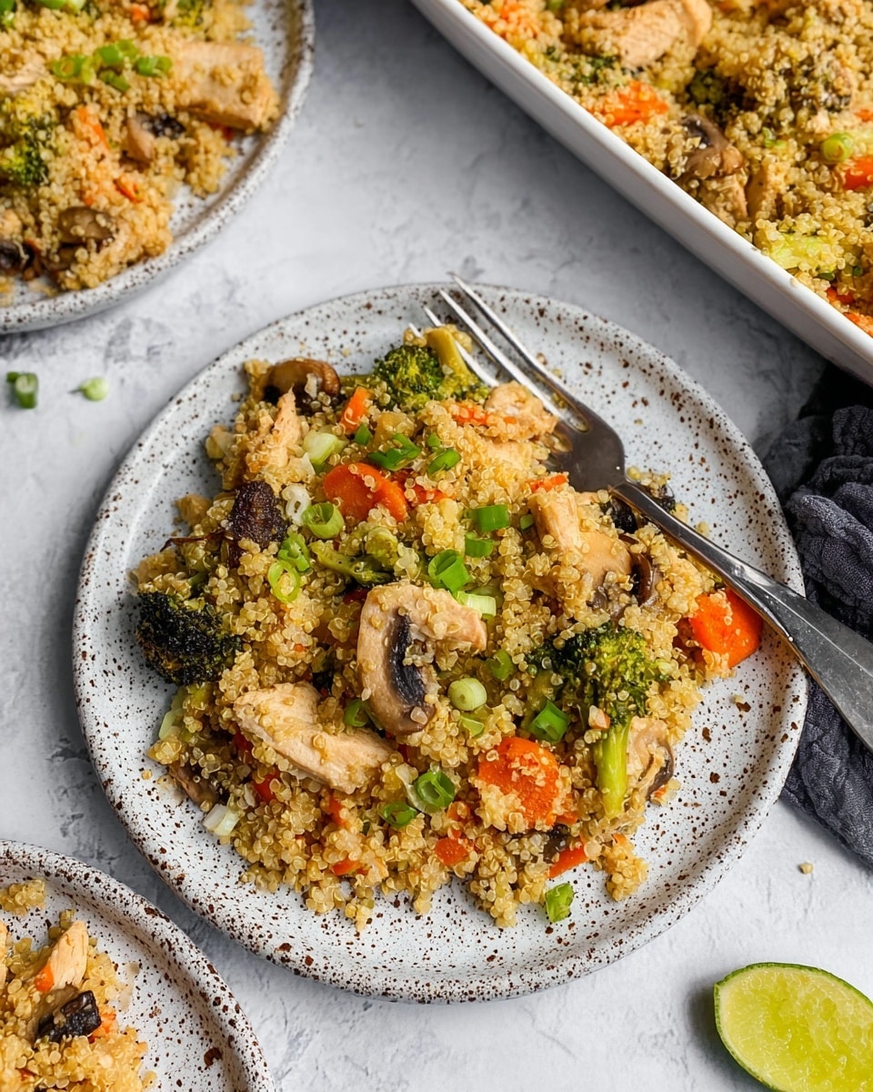 The image shows two white speckled plates and a white rectangular dish filled with a colorful quinoa stir-fry on a white marbled surface. Each plate has one layer of cooked quinoa mixed with small pieces of orange carrots, green broccoli florets, light brown mushrooms, and red bell pepper slices, topped with small chopped green onions. The vegetables and quinoa are well mixed, showing a variety of textures from soft quinoa to slightly crisp vegetables. A halved lime sits on the bottom right corner of the image, and a small bowl with sliced green onions is partially visible in the top left corner. A gray cloth napkin is seen near the rectangular dish. Photo taken with an iphone --ar 4:5 --v 7