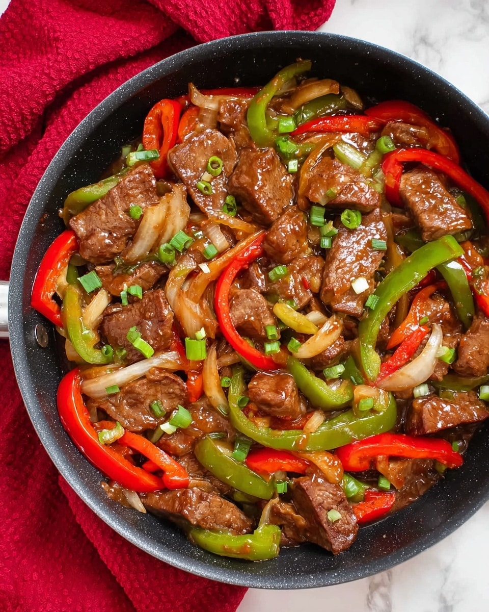 A black pan filled with cooked pieces of brown meat mixed with slices of red and green bell peppers and bits of white onion, all covered in a shiny sauce. The meat pieces are scattered throughout the pan, with the bell pepper slices curved and layered among them. Small green onion pieces are sprinkled on top. The pan sits on a white marbled surface with a red cloth in the background. photo taken with an iphone --ar 4:5 --v 7