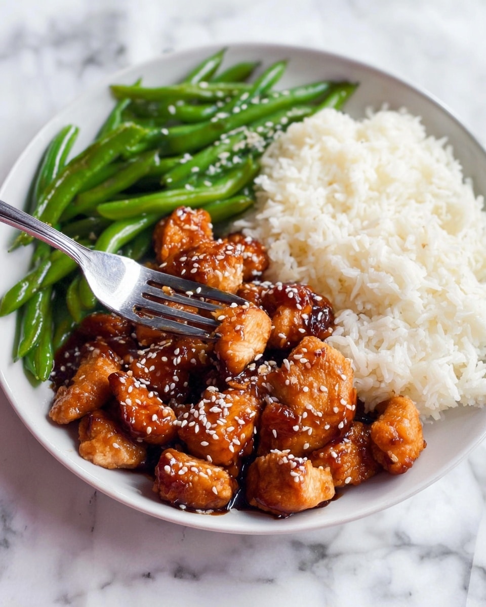 A white plate filled with three sections: fluffy white rice on the top right, dark brown glazed chicken pieces covered with white sesame seeds in the center, with a silver fork spearing one chicken piece, and bright green cooked green beans on the bottom right. The plate rests on a white marbled surface. Photo taken with an iphone --ar 4:5 --v 7