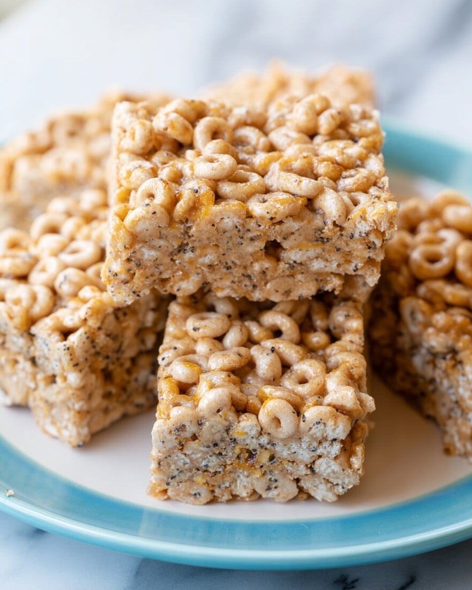 The image shows several square cereal bars made mainly of light brown Cheerios and other small seeds or grains, tightly packed together to form a solid block. Each bar has a rough, textured surface with visible round cereal pieces covering every part. The bars are stacked on a white plate with a blue inner color, all placed on a white marbled surface. The bars look soft but firm enough to hold their shape, with small bits of seeds visible throughout the bars. photo taken with an iphone --ar 4:5 --v 7