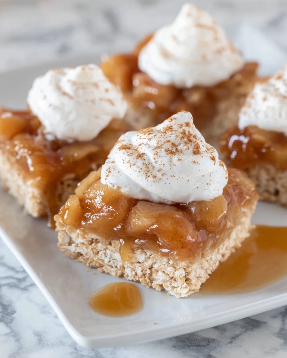The image shows three square pieces of light brown crispy treats arranged on a white plate with a white marbled surface underneath. Each treat has three layers: the bottom layer is a crunchy, light brown crispy base; the middle layer features a shiny, amber-brown apple topping with visible apple chunks covered in syrup; and the top layer is a dollop of smooth white whipped cream sprinkled with a light dusting of cinnamon. The syrup from the apple topping slightly drips onto the plate, adding a glossy texture to the scene. The focus is close up, highlighting the textures and colors clearly. Photo taken with an iphone --ar 4:5 --v 7