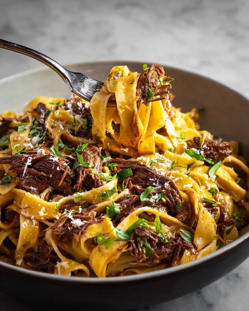 A close-up view of wide, flat pasta ribbons with a light yellow color mixed with dark brown shredded meat sauce spread evenly on top. The pasta and meat sauce are in a shiny metal pan with a dark handle, and sprinkled green fresh herbs add a touch of brightness. The background is a white marbled texture, and a black and white cloth is partly visible at the bottom right corner. Photo taken with an iphone --ar 4:5 --v 7