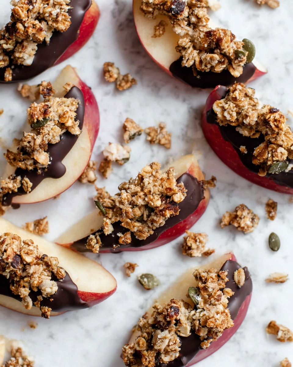 The image shows several apple slices arranged on crumpled white paper placed on a white marbled surface. Each apple slice has three layers: the base is a pale cream apple slice with red skin on the edge, the middle layer is a dark chocolate coating partially covering the apple, and the top layer is a rough, chunky granola mix with light brown oats and some pumpkin seeds scattered over the chocolate. Some granola crumbs are scattered around the slices. photo taken with an iphone --ar 4:5 --v 7