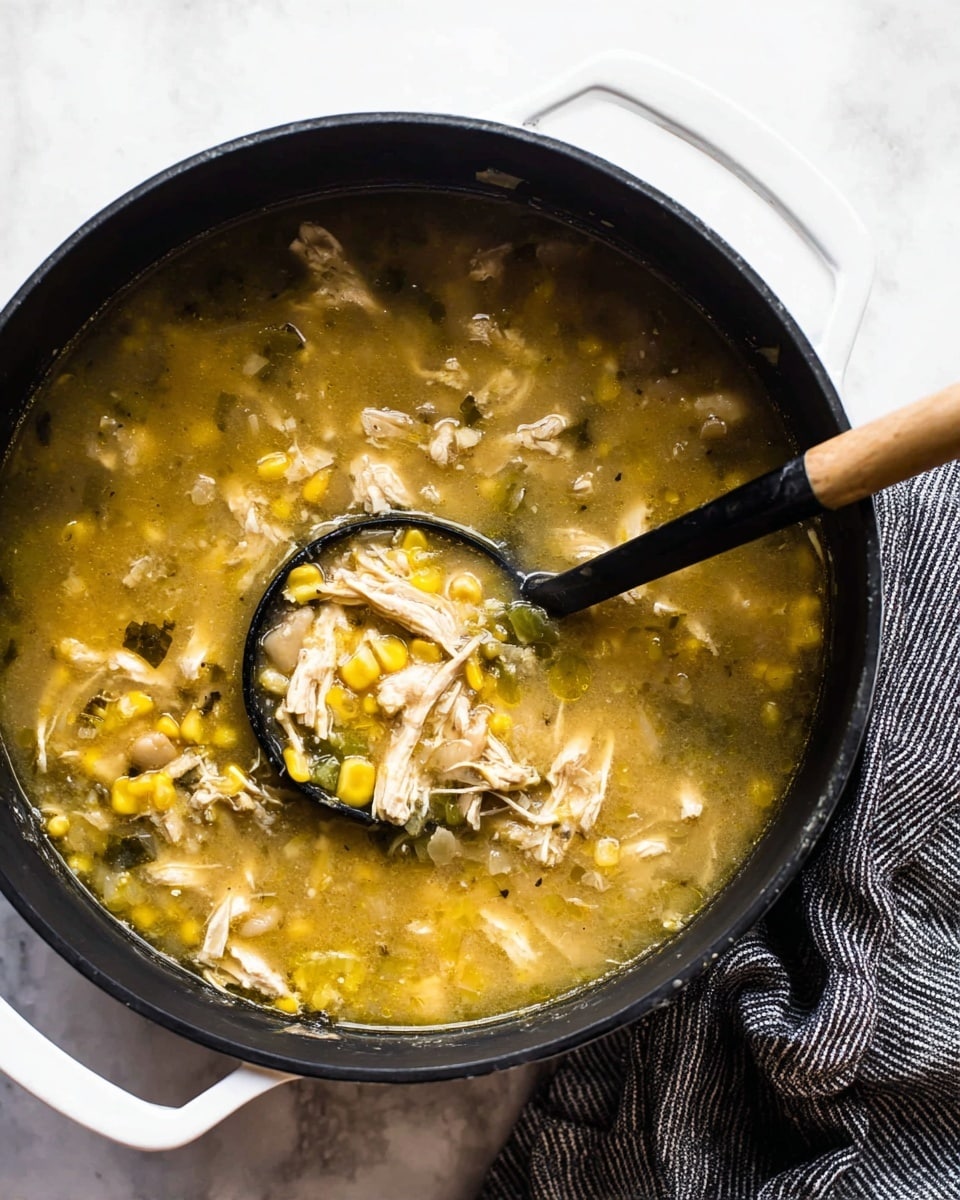 A close-up top view of a black pot filled with thick soup that has three main layers: a clear yellow broth base, shredded light brown chicken pieces spread evenly, and small chunks of yellow corn, beige beans, and green diced peppers mixed throughout. A black ladle with a wooden handle is scooping some soup showing a mix of all ingredients in it. The pot handle is white and the pot is placed on a white marbled surface with a gray striped cloth on the side. Photo taken with an iphone --ar 4:5 --v 7