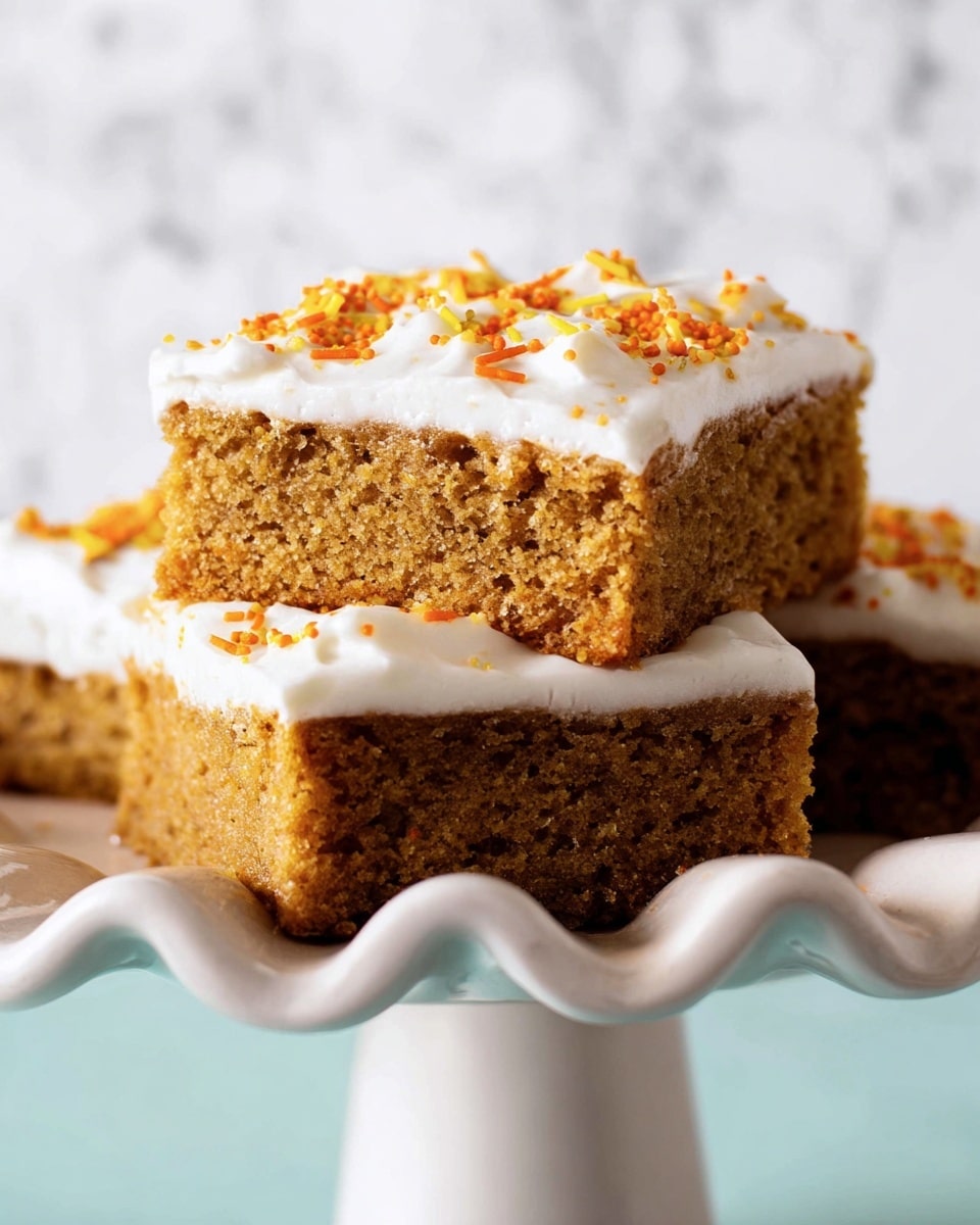 The image shows square cake pieces with two layers: a brown spongy cake base and a thick smooth white frosting layer on top. The frosting is decorated with small, colorful sprinkles in yellow, orange, white, and gold, scattered across the surface. Two of the squares have a small, round, orange pumpkin decoration with a smiling face and green stem made of many tiny pearl-like beads, placed near the center. One piece is lifted vertically revealing the inside moist cake texture and frosting. The cake pieces are arranged closely together on a white marbled surface, with one missing piece creating a small empty space. Photo taken with an iphone --ar 4:5 --v 7