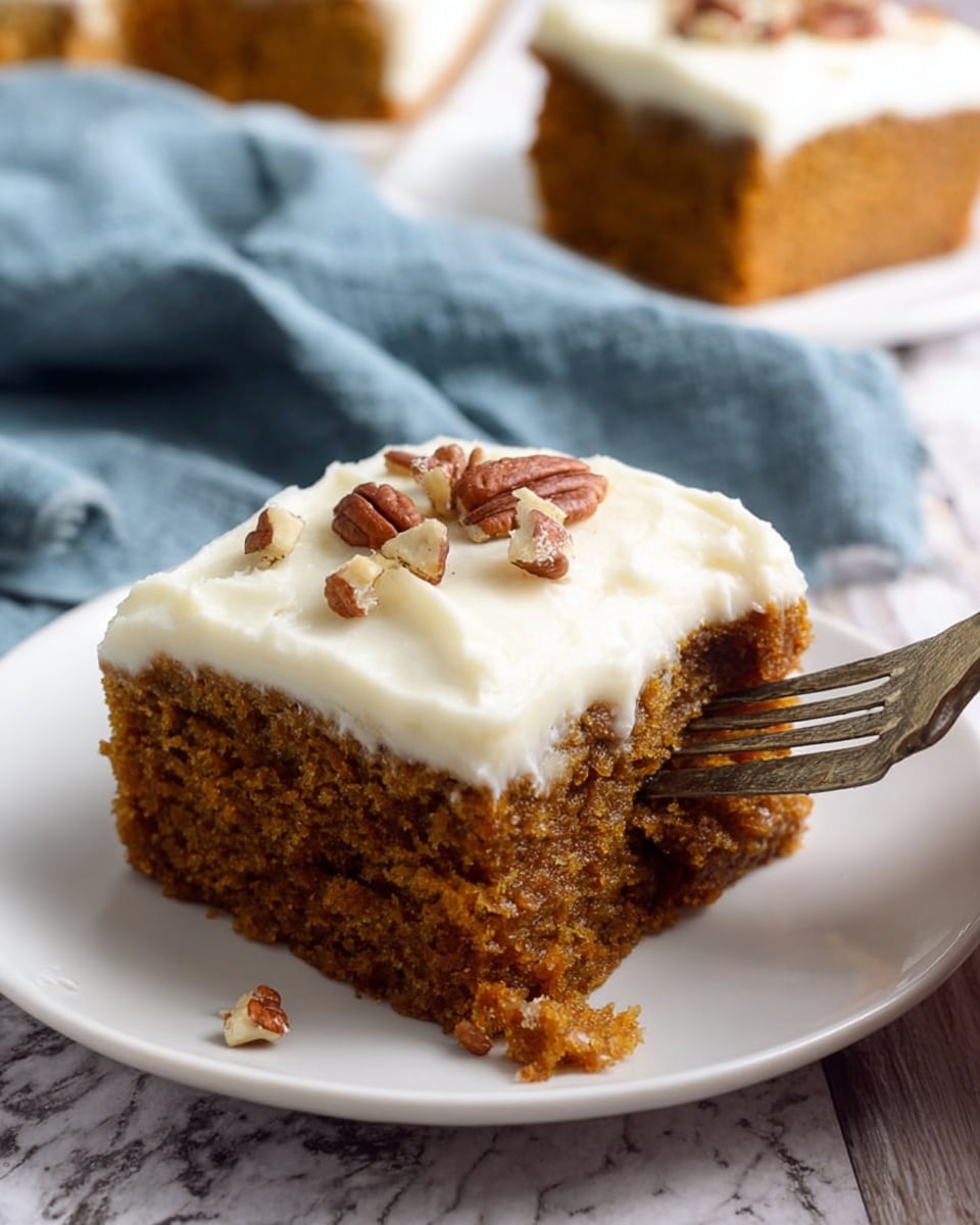 A single square piece of moist, brown cake with a rough texture is shown on a white plate, topped with a thick layer of smooth, white frosting. Small pieces of pecans are scattered on top of the frosting, adding a bit of texture and color contrast. Part of the cake has been broken off and is being held by a woman's hand using a fork. In the background, there is another plate with a similar piece of cake, and a soft blue cloth is loosely draped over a white marbled surface. Photo taken with an iphone --ar 4:5 --v 7