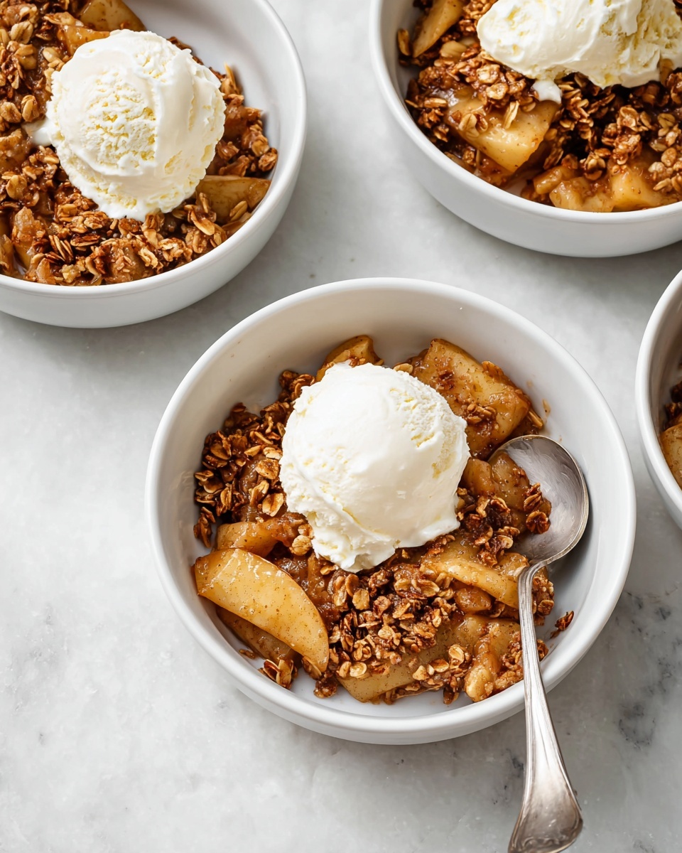 Three white bowls sit on a white marbled surface, each filled with warm apple crisp. The bottom layer shows soft, light brown baked apple slices mixed with darker, crunchy granola pieces speckled with oats. On top of this layer sits a single round scoop of creamy white ice cream, which is starting to melt slightly onto the apple mix below. A silver spoon rests inside the front bowl ready to scoop. The overall colors are warm browns and creamy whites, with the texture contrast between soft apples, crunchy granola, and smooth ice cream clear. Photo taken with an iphone --ar 4:5 --v 7