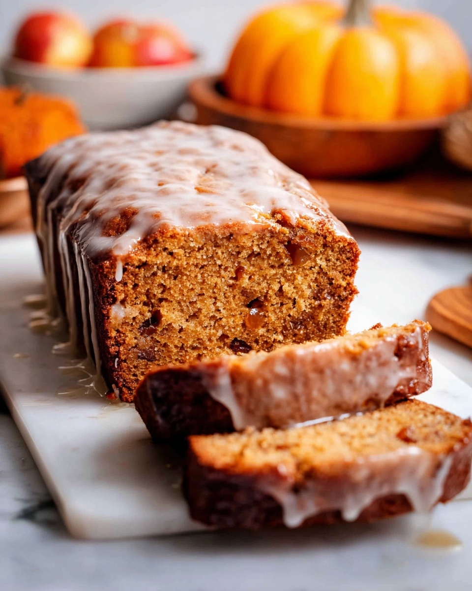 The image shows a loaf of brown cake with a shiny white glaze dripping down the top and sides, placed on a white marbled surface. The loaf appears moist and textured with small fruit or nut pieces visible inside. Three slices lie in front of the loaf, showing the soft, dense interior and the darker, slightly caramelized crust edges. In the background, out of focus, are small orange pumpkins and some apples in a bowl, adding an autumn feel to the scene. Photo taken with an iphone --ar 4:5 --v 7
