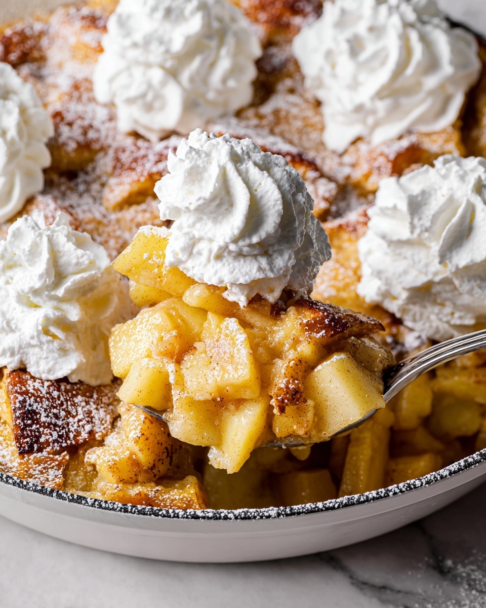 A close-up of a white pan filled with a warm apple dessert that has three layers: the bottom layer is soft and golden-yellow, the middle layer contains chunks of cooked light yellow apples, and the top layer is golden-brown crispy pieces dusted with white powdered sugar. On top, there are three large dollops of white whipped cream, fluffy and swirl-textured, placed on different spots. A silver spoon is partially serving a piece from the pan, showing the different textured layers clearly. The pan rests on a table with a white marbled texture underneath. Photo taken with an iphone --ar 4:5 --v 7
