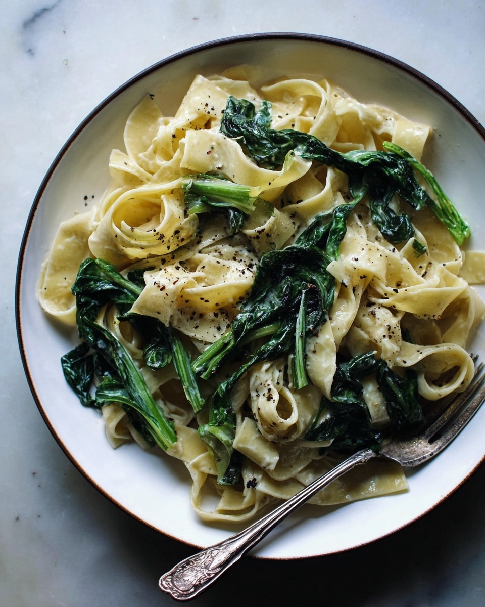 A white pan with blue handles filled with a pasta dish visually layered with wide, flat pale yellow noodles twisted and folded throughout, fresh green stems and dark green leafy vegetables mixed evenly on top of and between the noodles, all lightly speckled with coarse black pepper for texture and color contrast, and a pair of metal tongs resting inside the pan partially lifting some noodles and greens; the pan sits on a dark wooden surface. photo taken with an iphone --ar 4:5 --v 7