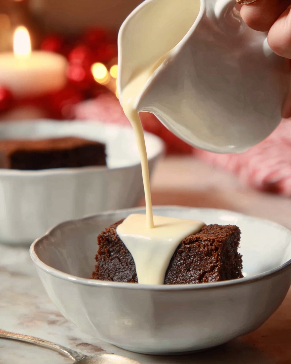 A triangular slice of dark brown fruitcake filled with bits of dried fruit takes the front spot on a white plate decorated with green leaves and red berries. Next to the cake slice sits a smooth pale yellow dollop of butter or cream. Behind this, a larger, round fruitcake with a dark brown color and glossy texture is visible with a green holly decoration on top, placed on a larger white plate. All is set on a white marbled surface with a festive tablecloth underneath. photo taken with an iphone --ar 4:5 --v 7