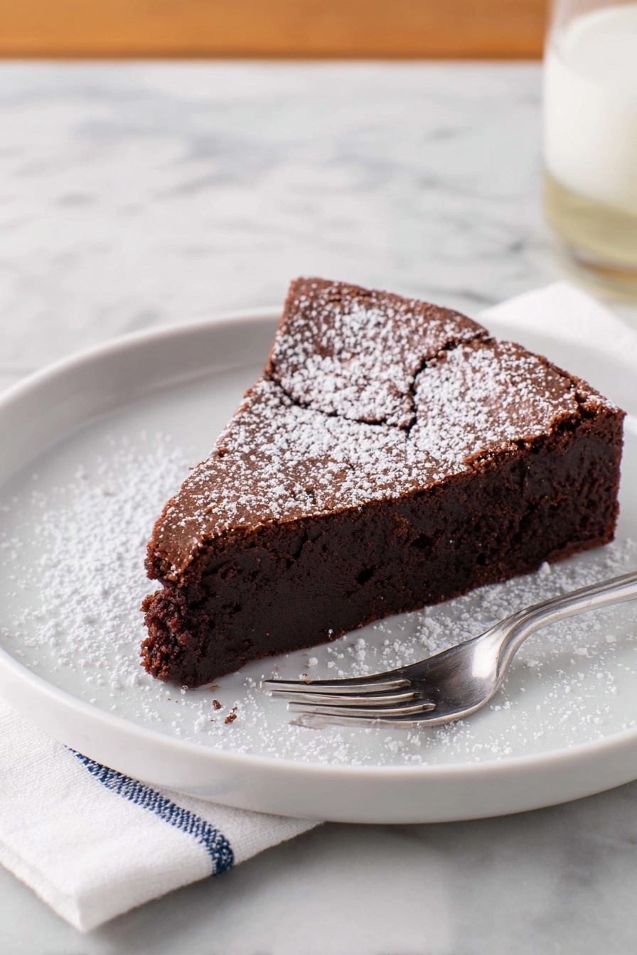 A single slice of dark brown chocolate cake with a slightly cracked top layer is placed on a white plate. The cake has one thick layer that looks moist and dense, dusted with a light sprinkle of white powdered sugar on top and around the plate. A silver fork rests on the plate next to the cake. The plate sits on a white marbled surface with a white napkin with blue stitching beside it. Photo taken with an iphone --ar 2:3 --v 7 - Flourless Chocolate Torte, gluten-free chocolate dessert, rich chocolate torte, decadent flourless cake, easy gluten-free dessert