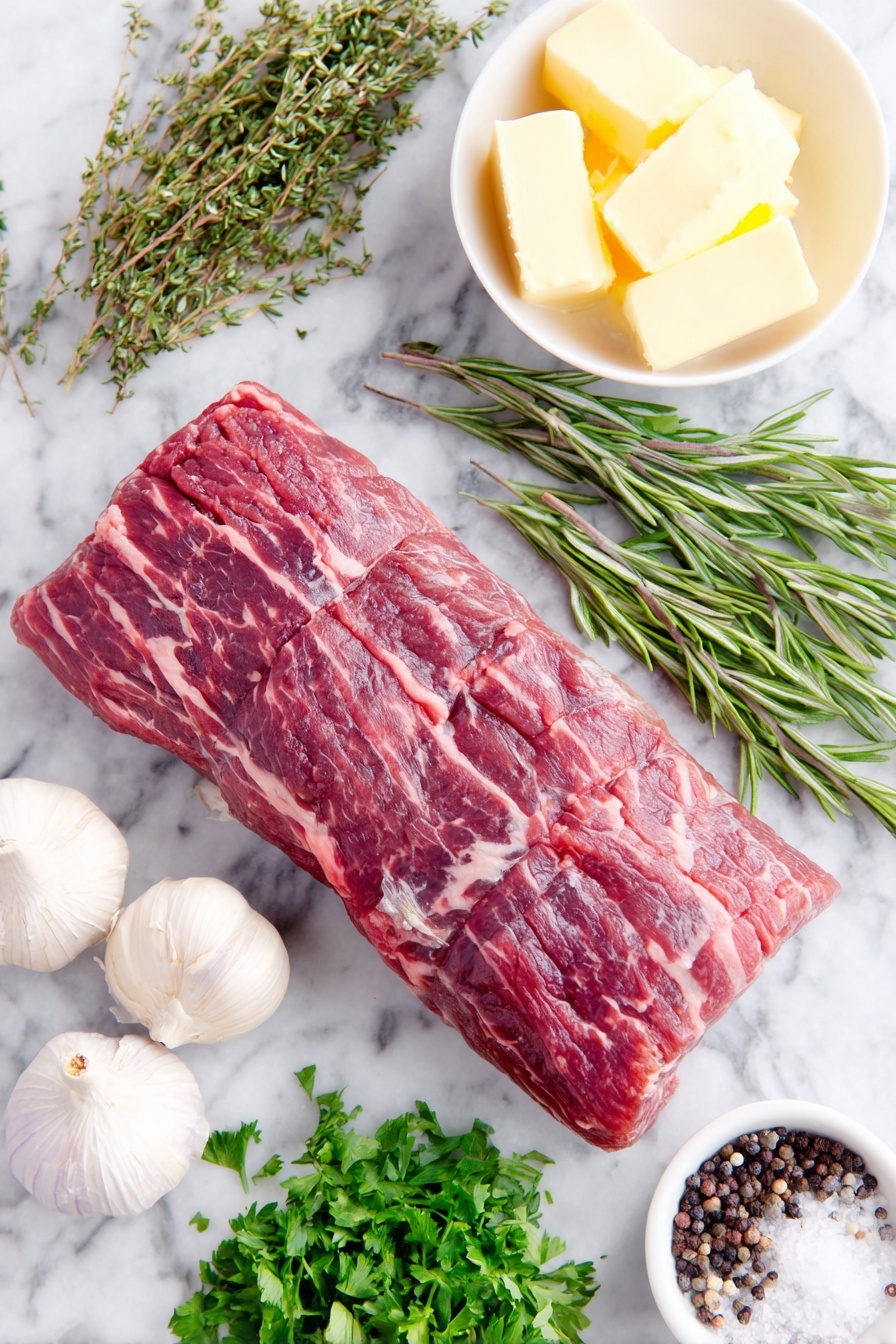 Flat lay of a whole trimmed beef tenderloin roast with a rich red color and fine marbling, three whole uncracked garlic cloves with smooth white skins, a small heap of fresh flat-leaf parsley sprigs, fresh rosemary sprigs with needle-like leaves, fresh oregano sprigs with small green leaves, a few whole black peppercorns scattered naturally, a small white ceramic bowl holding softened pale yellow butter, a small white bowl with dark glossy balsamic vinegar, a small white bowl of thick Worcestershire sauce with a deep brown hue, and a small pile of coarse sea salt crystals, all arranged symmetrically with perfect balance, placed on a clean white marble surface, soft natural light, photo taken with an iPhone, professional food photography style, fresh ingredients, white ceramic bowls, no bottles, no duplicates, no utensils, no packaging --ar 2:3 --v 7 --p m7354615311229779997 - Oven-Roasted Beef Tenderloin with Garlic Butter, beef tenderloin main dish, elegant beef roast recipe, holiday beef centerpiece, juicy beef tenderloin