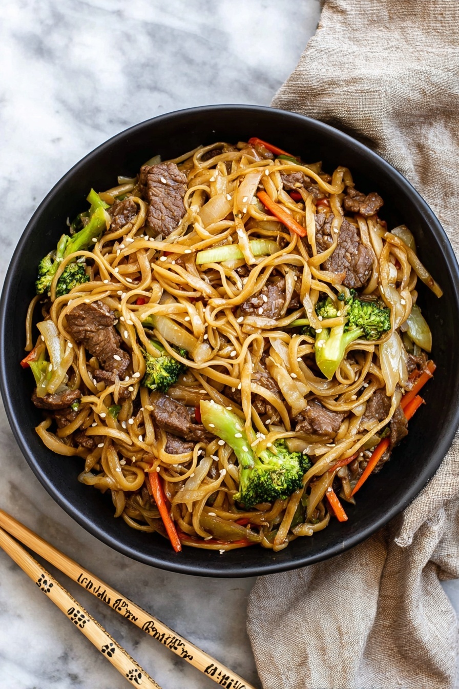 A black bowl filled with stir-fried noodles mixed with pieces of beef, bright green broccoli florets, thin orange carrot strips, and light brown cooked onions, all coated in a light sauce giving a slight shine; the noodles are long and a pale tan color, twisting through the vegetables and meat, garnished with small white sesame seeds. The bowl sits on a white marbled surface next to a pair of light wooden chopsticks decorated with simple patterns, and a beige cloth napkin is casually placed nearby. photo taken with an iphone --ar 2:3 --v 7 - Beef Lo Mein Stir-Fry, easy beef stir-fry recipe, quick Asian noodle dish, healthy beef and vegetable stir-fry, savory noodle stir-fry ideas