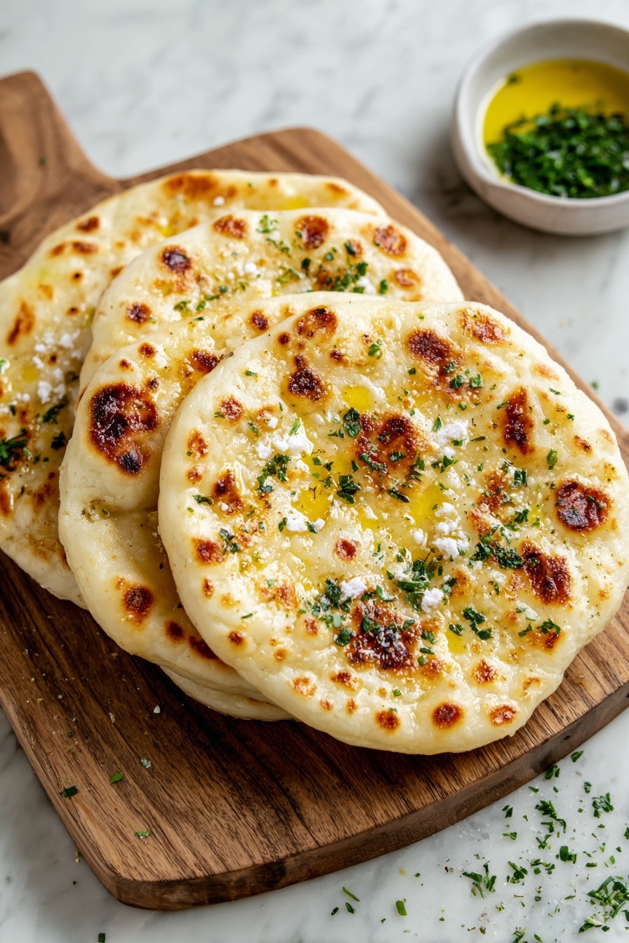 Four flat round breads with golden brown spots lay stacked on a wooden board, each topped with melted butter and small bits of white cheese sprinkled with chopped green herbs. The wooden board sits on a white marbled surface, with a small bowl of oil and some scattered herbs nearby. photo taken with an iphone --ar 2:3 --v 7 - Cottage Cheese Flatbread, easy flatbread recipe, quick flatbread, homemade flatbread, soft flatbread recipes