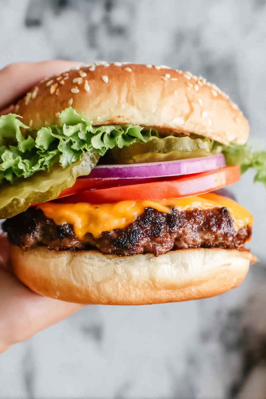 A close-up view of a burger held by a woman's hand with a sesame seed white bun on top. Under the top bun, there are green pickles, light purple onion rings, and wavy green lettuce. Below the lettuce, there is a bright red slice of tomato. Beneath the tomato is a layer of melted orange cheese covering a grilled dark brown beef patty with textured grill marks. The bottom is a smooth white bun. The background shows a white marbled surface. Photo taken with an iphone --ar 2:3 --v 7 - Ultimate Beef Burger, beef burger recipe, homemade beef burger, juicy burger patties, flavorful burger idea